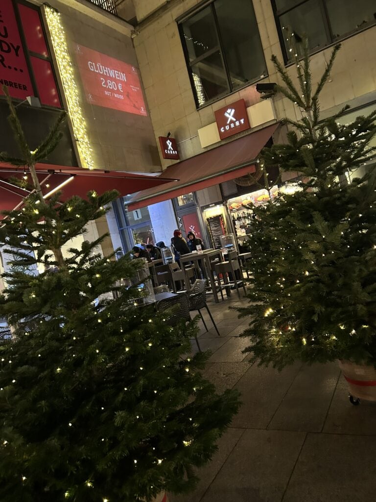 Weihnachtlich dekorierter Außenbereich von CURRY am Schloss mit Glühwein-Hinweis und winterlicher Abendstimmung